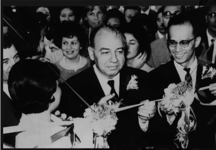 黑白剪彩合影:中间与右侧两名男子手持剪刀和彩带,周围站着参加仪式的人群。